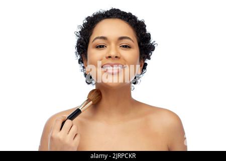 femme avec brosse à maquillage qui applique un effet brillant sur la peau Banque D'Images