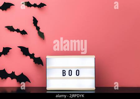 Décoration d'Halloween sur mur rose, visionneuse avec message « Boo » et silhouettes de chauves-souris noires effrayantes. Banque D'Images