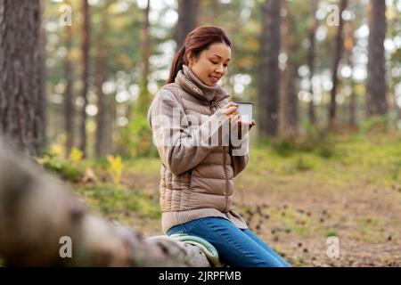 femme asiatique avec mug buvant du thé dans la forêt Banque D'Images