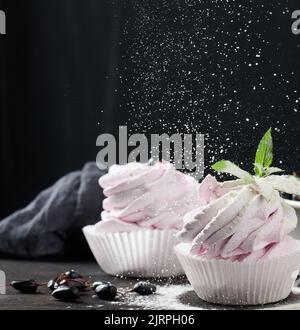 Marshmallows aux fruits martionnés dans une tasse en papier sur un plateau en bois noir, délicieux dessert Banque D'Images