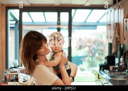 Jeune mère caucasienne tenant son bébé dans la cuisine. Bon moment, espace de copie. Banque D'Images