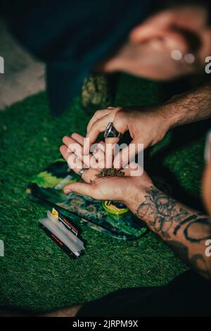 Un mec tatoué qui roulait un joint de marijuana Banque D'Images