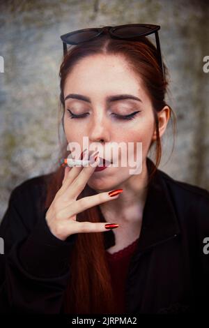 Gros plan d'une fille à cheveux rouges qui fume un joint Banque D'Images