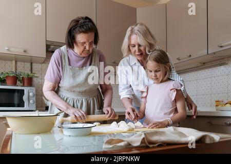 Trois femmes dans la cuisine cuisent des tartes ensemble. Banque D'Images