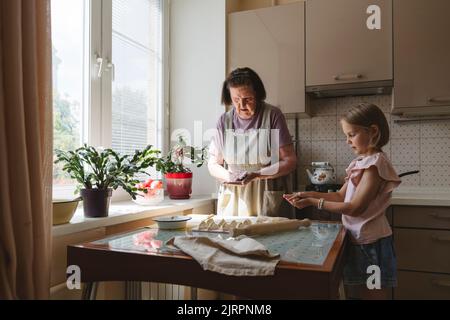 Les tourtes de la grande-mère et de la petite-fille cuisinent ensemble dans la cuisine. Banque D'Images