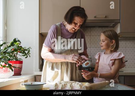 La grande-grand-mère enseigne à sa petite-fille la cuisson des tartes. Banque D'Images