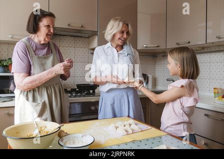 Trois générations de femmes cuisent des tartes dans la cuisine. Banque D'Images