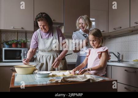 Trois générations de femmes cuisinent ensemble dans la cuisine. Banque D'Images