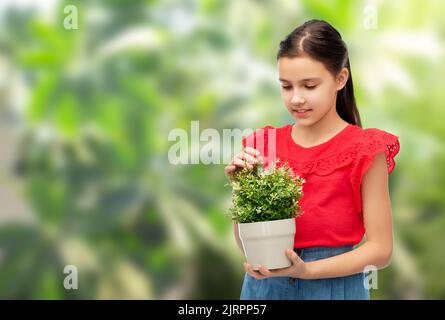 bonne fille souriante tenant la fleur verte dans le pot Banque D'Images