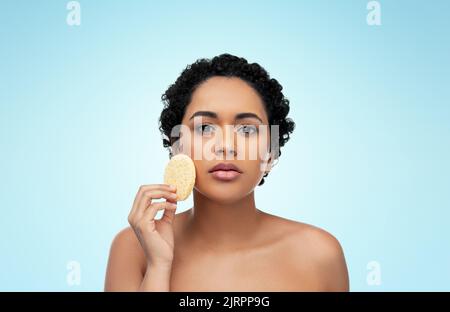 Jeune femme en train de nettoyer le visage avec une éponge exfoliante Banque D'Images