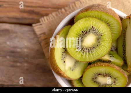 Vue de dessus des tranches de kiwi dans un bol blanc sur la table. Banque D'Images