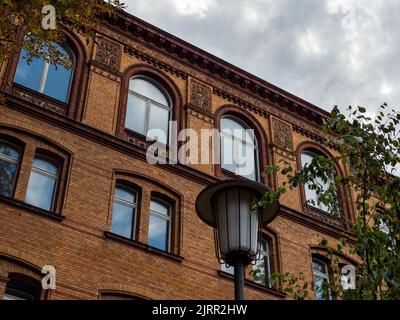 Extérieur du bâtiment ancien avec éléments architecturaux rétro sur la façade. Mur de clinker jaune avec des reflets dans les fenêtres et un ciel couvert. Banque D'Images