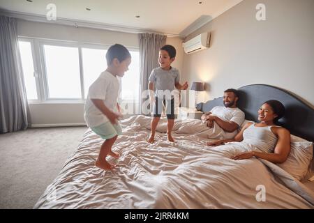 Mère, père et enfants sautent sur le lit ou la chambre et se réveillent heureux ensemble dans la maison familiale le matin. Bonheur, amour et sourire des enfants avec Banque D'Images