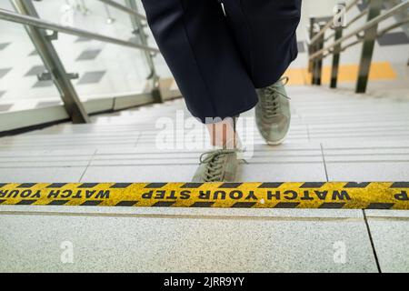 Observez l'autocollant de votre marchepied sur les escaliers de l'espace public avec une personne qui marche dans les escaliers Banque D'Images