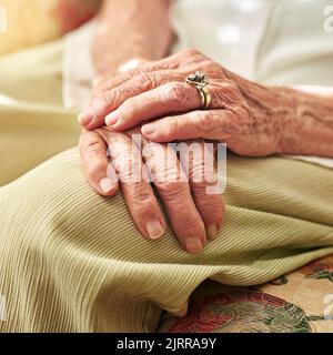 Le passage du temps peut être vu dans les mains d'un womans âgé se reposant sur ses genoux. Banque D'Images