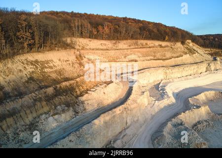 Vue aérienne d'une mine à ciel ouvert de matériaux de grès pour l'industrie de la construction avec excavateurs et camions à benne basculante. Équipement lourd dans l'exploitation minière et Banque D'Images