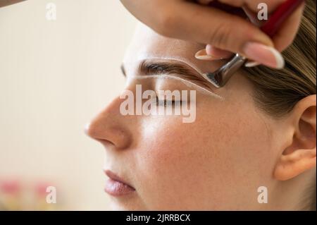 Le maître dessine la forme des sourcils avec de la peinture blanche avant de colorer. Banque D'Images