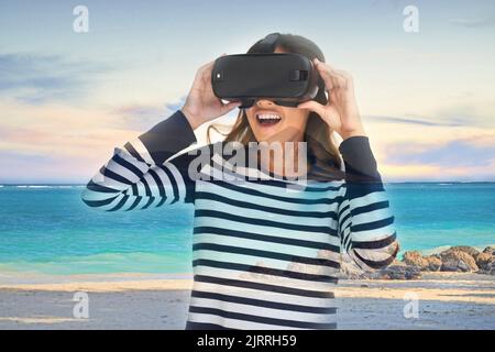 Plus besoin d'imaginer : une jeune femme portant un casque VR superposé sur un paysage de plage. Banque D'Images