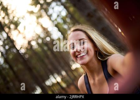 Prise de selfies dans la nature. Portrait d'une jeune femme heureuse prenant un selfie tout en explorant une forêt par elle-même. Banque D'Images