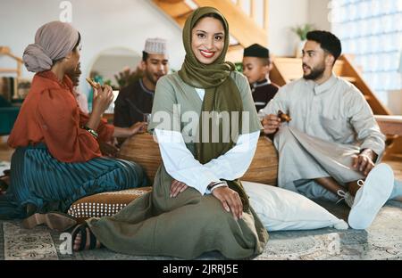 Une heureuse femme musulmane assise, avec la famille et la célébration de la culture pendant le ramadan. Une femme islamique moderne avec un sourire, une beauté et dans un hijab à Banque D'Images