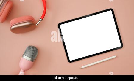 Tablette numérique plate, casque sans fil et microphone sur fond rose. Radio, podcasts, blogging et concept de technologie Banque D'Images