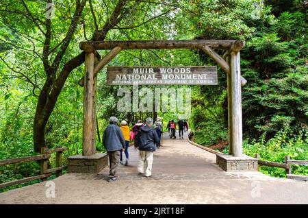 Personnes entrant dans Muir Woods passant sous un panneau suspendu du haut d'une porte en bois à l'entrée des bois. Banque D'Images