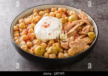 Lablabi Tunisien pois chiches ragoût d'olive verte, de thon en conserve et d'œuf poché dans le bol de la table. Horizontale Banque D'Images