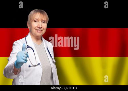 Femme allemande souriante et mûre médecin portant un stéthoscope sur le drapeau de l'Allemagne Banque D'Images