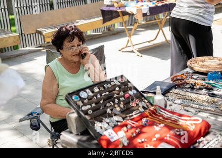 Happy Woman parle par téléphone tout en vendant des bijoux vintage sur le marché aux puces en Géorgie Banque D'Images