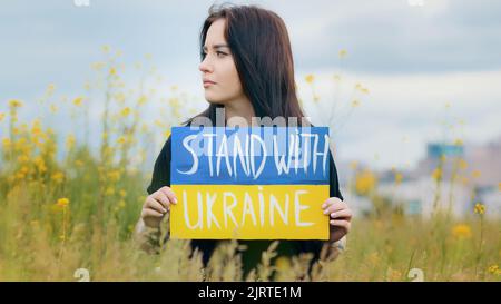 Portrait en plein air profil femelle visage bouleversé femme patriotique fille tenir carton coloré écrit inscription stand avec l'Ukraine montrant symbolique Banque D'Images