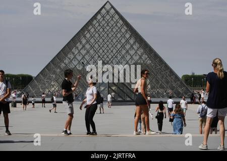 Les touristes apprécient près de Pyramide au Musée du Louvre pendant une chaude journée d'été avec 30 degrés Celsius sur 25 août 2022 à Paris, France. Banque D'Images