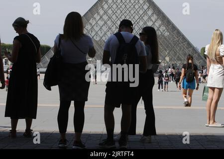 Les touristes apprécient près de Pyramide au Musée du Louvre pendant une chaude journée d'été avec 30 degrés Celsius sur 25 août 2022 à Paris, France. Banque D'Images