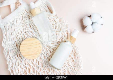 Crème hydratante bocal, sérum en bouteille de verre et toner avec fleur de coton sur fond beige. Flat lay, vue de dessus. Kit pour soins de la peau et du corps beauté p Banque D'Images