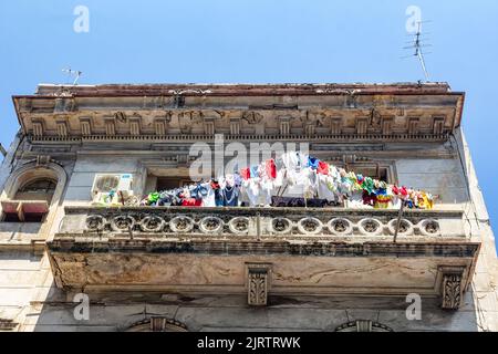 Vue à angle bas d'une corde à linge sur un balcon d'une façade de bâtiment abîmé Banque D'Images