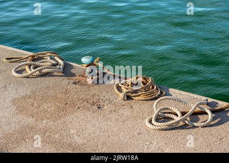 Gros plan d'un bollard d'amarrage rouillé avec des cordes ou des colporteurs sur le quai du port. Golfe de la Spezia, Ligurie, Italie, Europe. Banque D'Images