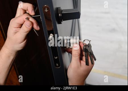 Le maître installe le noyau de la serrure de porte, le travail d'assemblage avec la porte, le noyau avec les clés. Banque D'Images