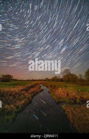 Une photo verticale des magnifiques pistes d'étoiles au-dessus de la rivière. Banque D'Images