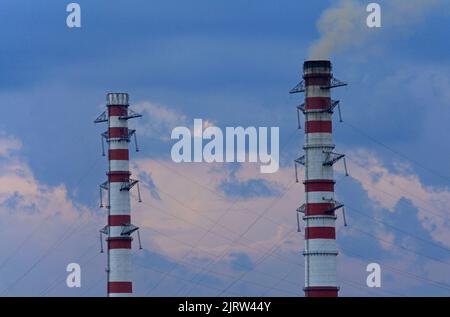 Des cheminées fumeurs sur fond de ciel d'hiver. Saison de chauffage. La vue des sommets de cheminée de la station thermique avec des bouffées de fumée Banque D'Images