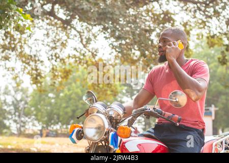 homme africain sur une moto faisant un appel téléphonique Banque D'Images