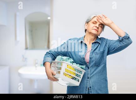 femme âgée fatiguée avec panier à linge Banque D'Images