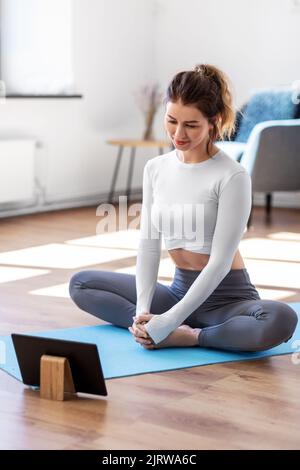 jeune femme avec un pc tablette faisant du yoga à la maison Banque D'Images