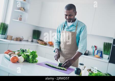 Photo de drôle d'âge positif homme porter un tablier préparer le souper couper des légumes savoureux à l'intérieur de la pièce maison Banque D'Images