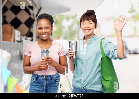 les femmes avec des gobelets et des sacs au-dessus du camion alimentaire Banque D'Images
