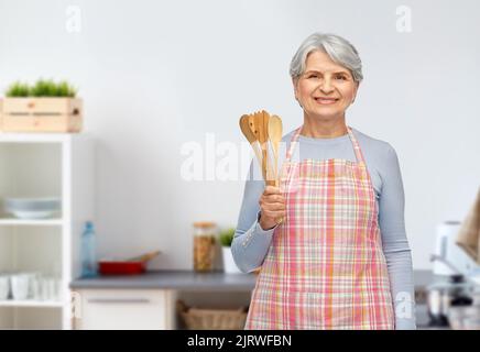 femme âgée souriante avec des cuillères en bois dans la cuisine Banque D'Images