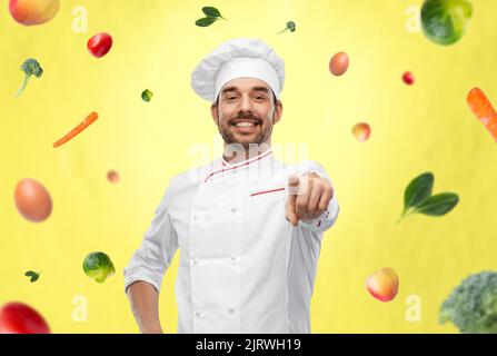 joyeux chef masculin souriant en toque vous pointant vers vous Banque D'Images
