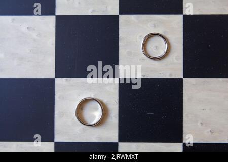 Deux anneaux de mariage reposent sur un échiquier, Banque D'Images