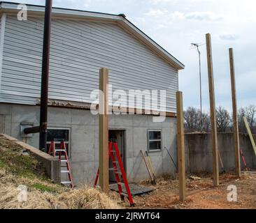 Des trous ont été creusés et les grands poteaux en bois ont été mis dans le sol. La construction d'une nouvelle pièce à l'extrémité de cette maison commencera bientôt. Banque D'Images