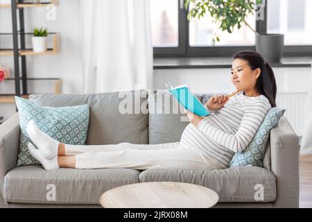 femme enceinte écrivant à l'agenda à la maison Banque D'Images