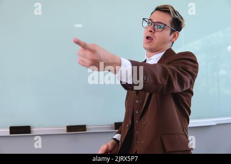 Enseignant excité tout en donnant une classe. Professeur donnant la parole à l'un de ses élèves. Professeur d'université pointant vers ses étudiants. Photo de haute qualité Banque D'Images