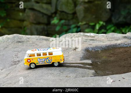 Jaune VW Camper van modèle de bus, dans une scène de la nature, sur un rocher, la conduite hors d'une flaque d'eau. Banque D'Images